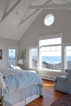 a bedroom with a large bed and two windows overlooking the ocean is pictured in this image