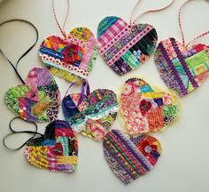 several heart shaped ornaments hanging from strings on a white counter top, one is made out of fabric and the other has various patterns