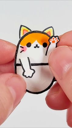 a person is holding a small sticker with a cat on it