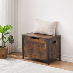 a wooden box with a cushion on it next to a potted plant