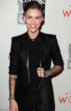 a woman with tattoos on her arm holding an umbrella in front of a white wall