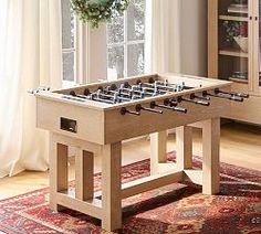 a table with foosball on it in front of a bookcase and window