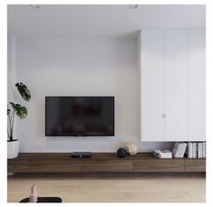 a flat screen tv sitting on top of a wooden entertainment center next to a plant