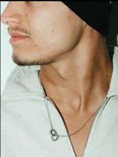 a close up of a person wearing a beanie and a necklace with a circle on it