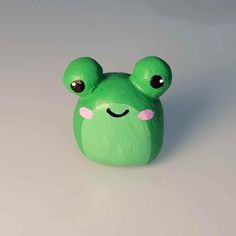 a green frog with big eyes sitting on top of a table