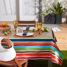 the table is set with plates and bowls of fruit, vegetables, and wine glasses