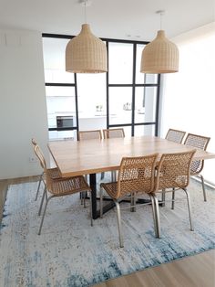 a dining room table and chairs in front of a large window with an area rug on the floor