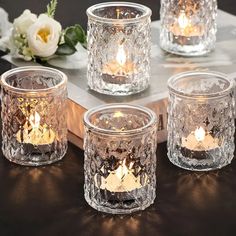 four clear glass tealight candles on a table