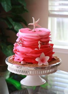 a cake with pink icing and white flowers on the top is sitting on a plate