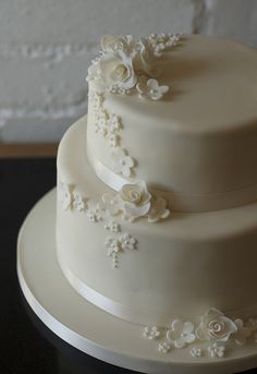 a three tiered cake with white flowers on it