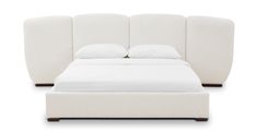 the bed is made up with white sheets and pillows on it's headboard