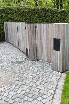 a wooden fence that is next to a brick walkway and green grass on the other side