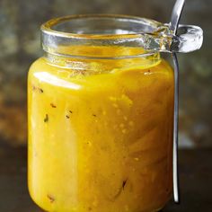 a glass jar filled with yellow liquid and a spoon in the top right hand corner