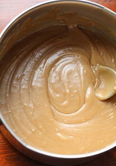 a metal bowl filled with peanut butter on top of a wooden table