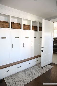 a room with some white cabinets and baskets on the top one wall, and a blue rug in front of it