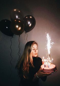 a woman holding a birthday cake with lit candles