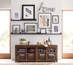 a living room with pictures hanging on the wall and shelves above it that have wine bottles