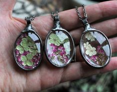 three necklaces with flowers in them on a person's hand