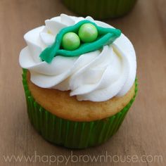 two cupcakes with white frosting and green decorations