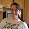 a woman wearing glasses standing in a kitchen