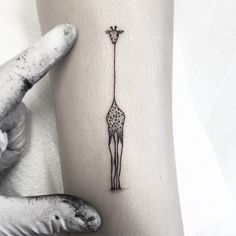 a giraffe standing next to a tall pole tattoo on the left inner arm