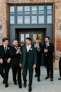 a group of men standing next to each other in front of a building with windows