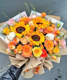 a bouquet of sunflowers and roses is held by someone