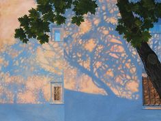 the shadow of a tree is cast on a blue wall with windows and a window sill