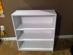 a white book shelf sitting on top of a carpeted floor next to a wall