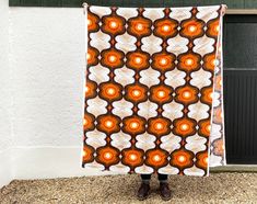 a person standing in front of a building holding up a large orange and white blanket