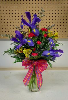 a vase filled with purple, yellow and red flowers