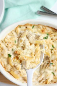 a spoon full of pasta and cheese casserole on a white plate with silverware