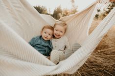 two young children are sitting in a hammock