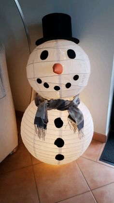 a snowman made out of paper lanterns on the floor