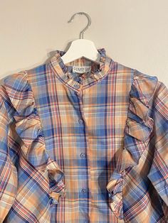 Vintage Private Line Plaid Ruffle Shirt! Pink/blue plaid print with long sleeves, ruffles along the chest, and buttons up the front. No size tag, but would best fit a medium, please refer to measurements. In excellent vintage condition! Approx. Measurements: Underarm to Underarm: 21" Sleeve Length: 23.5" Length: 25" Plaid Long Sleeve Blouse With Ruffles, Fall Button-up Ruffled Shirt, Fall Button-up Shirt With Ruffles, Fall Ruffle Button-up Shirt, Fall Ruffled Button-up Shirt, Casual Plaid Blouse With Ruffles, Fall Plaid Top With Ruffles, Blue Long Sleeve Ruffled Shirt, Fall Plaid Ruffled Tops