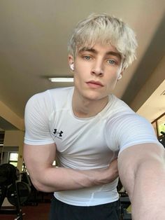 a young man with blonde hair and blue eyes is posing for a photo in the gym