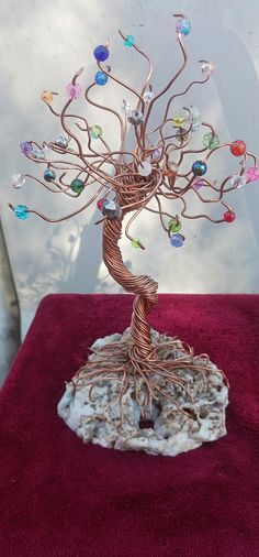 a wire tree sculpture with multicolored glass beads on it's branches and roots