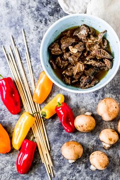 an assortment of vegetables and chopsticks on a counter top next to some meat