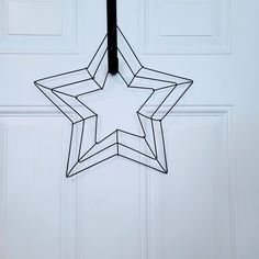 a metal star hanging from the side of a white door with a black pole in front of it