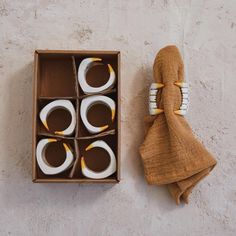 four candles are in a box on the floor next to a towel and some napkins