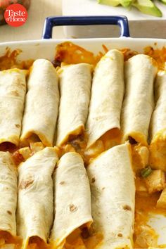 several burritos in a casserole dish with cheese and sauce on the side