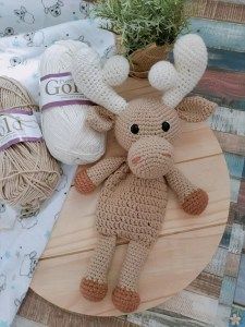 a crocheted stuffed animal laying on top of a wooden plate next to yarn