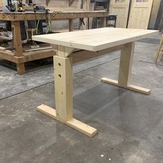 a wooden table sitting on top of a floor next to a workbench in a garage