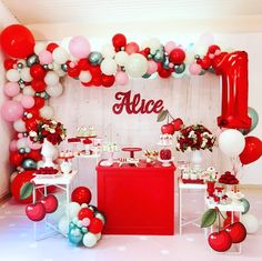 a table topped with lots of red and white balloons next to a sign that says alice