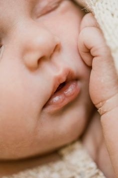 a close up of a baby's face with its eyes closed and hands on her head