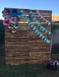 a wooden fence decorated with paper flowers and bunting