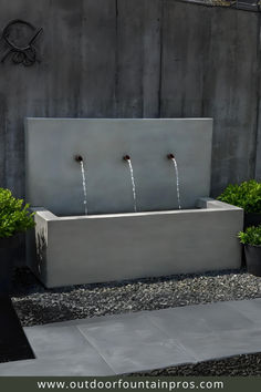 an outdoor fountain with three water jets running from it's sides into the ground