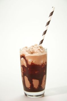 a glass with ice cream and chocolate milkshake in it on a white surface