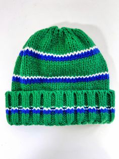 a green knitted hat with blue and white stripes on the front, against a white background