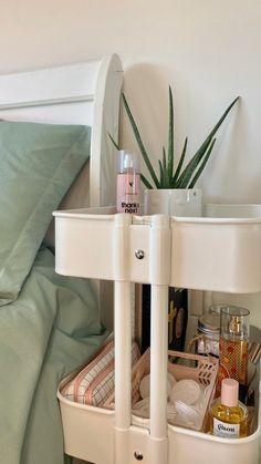 a bed with a plant on top of it next to a white shelf filled with personal care items